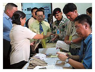 Comelec officials observe the opening of sealed envelopes containing local absentee votes